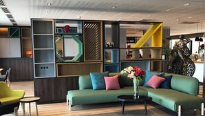 Un espace détente moderne avec un canapé vert, une petite table ronde et un vase de fleurs.