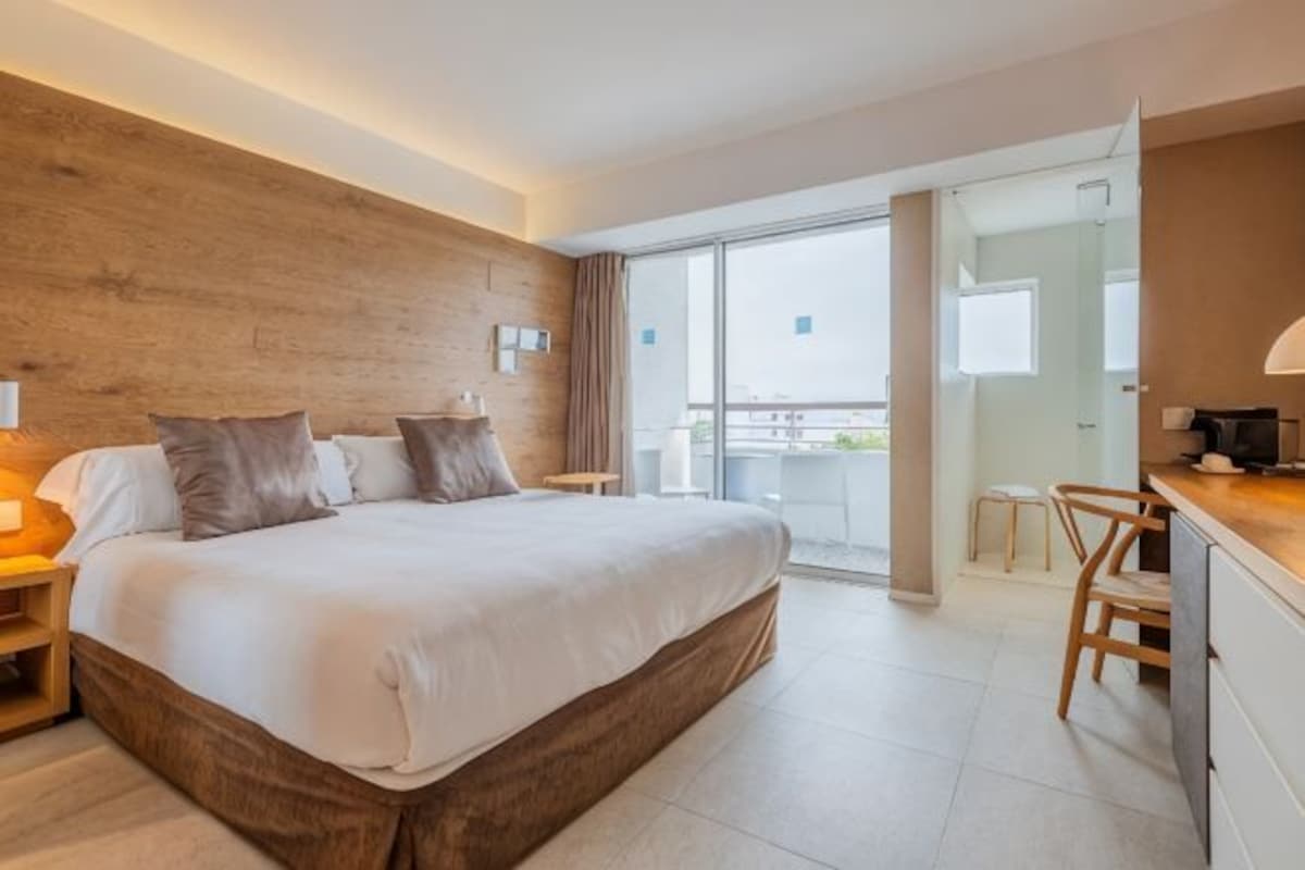 Habitación de hotel con una cama grande, un escritorio, una silla, un balcón y una pared de madera.