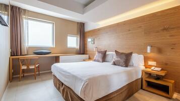 Una habitación de hotel moderna con una cama grande, un escritorio y una computadora.