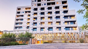 Un hotel de varios pisos con balcones, una placa con el nombre en la parte superior y una entrada con portones.