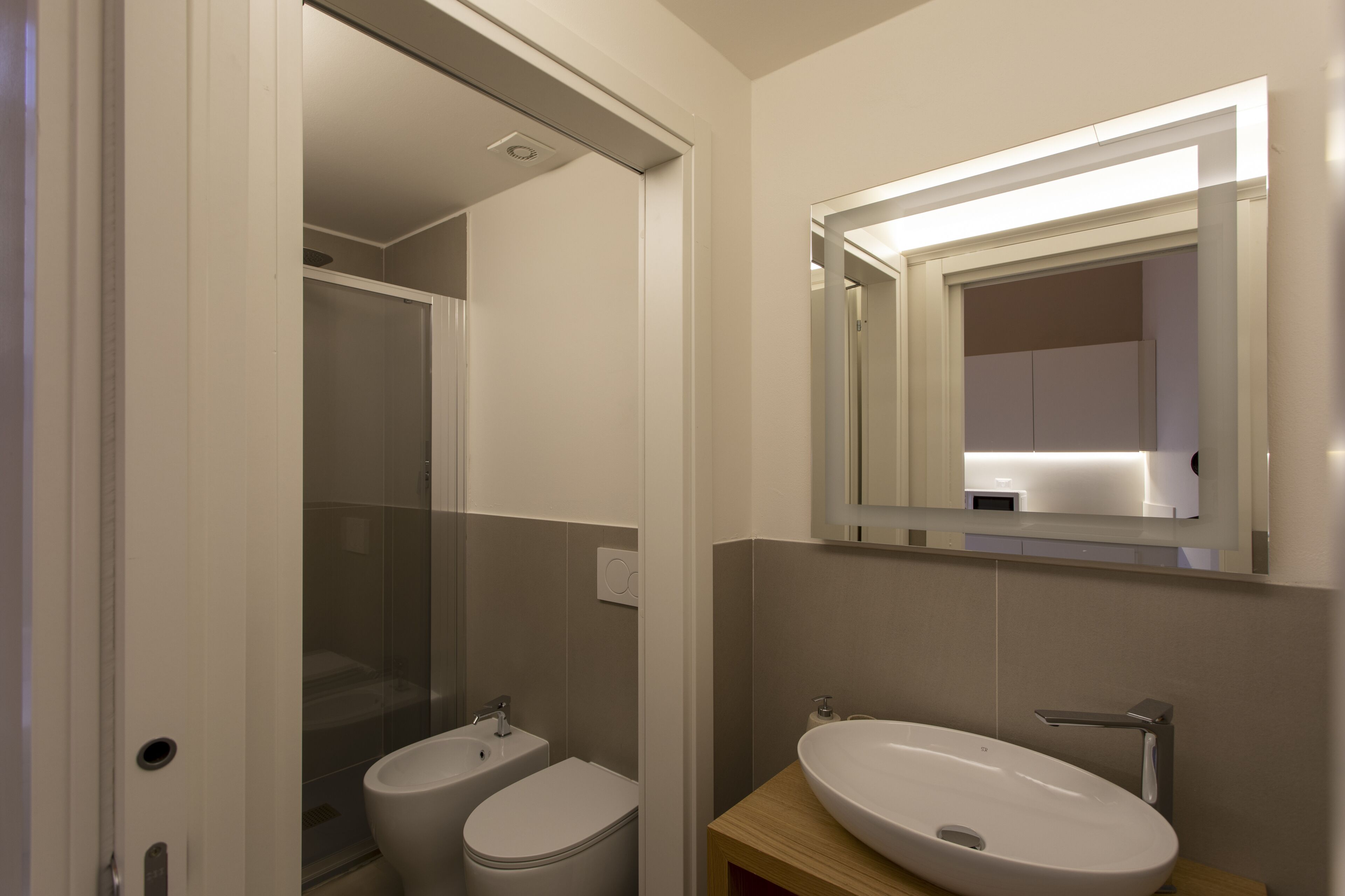 Un baño moderno con un lavamanos blanco, un espejo y una ducha.