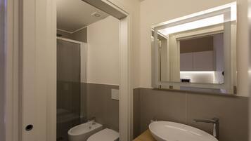 Un baño moderno con un lavamanos blanco, un espejo y una ducha.