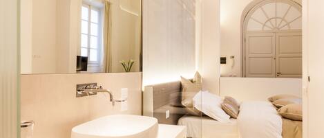 A modern bathroom with a large mirror, a round sink, and a glass shower enclosure.