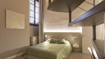 A modern bedroom with a bed, a nightstand, a window with curtains, and a staircase.