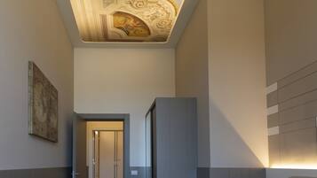 Ein Flur mit einer verzierten Decke, einer Tür zu einem anderen Raum und einem an der Wand befestigten Kunstwerk.