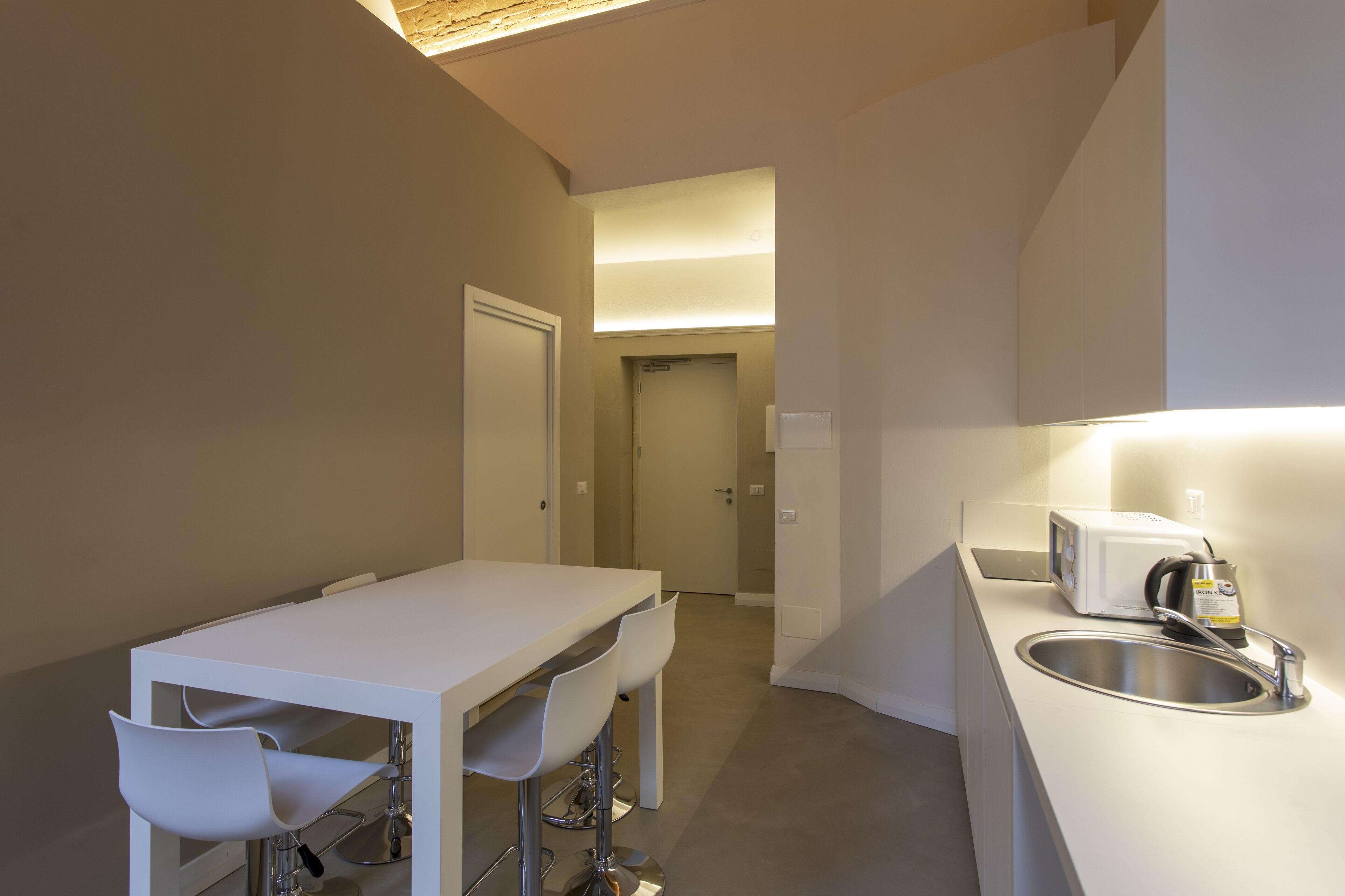 Eine moderne Küche mit weißer Arbeitsplatte, integriertem Spülbecken und einer Mikrowelle.