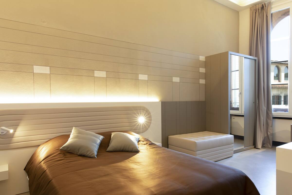 Ein modernes Hotelzimmer mit einem großen Bett, einer kleinen Sitzecke und einem Kleiderschrank.