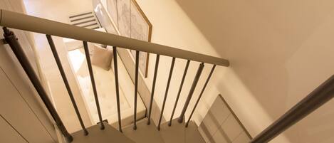 A spiral staircase with a handrail, beige walls, and a light-colored floor.