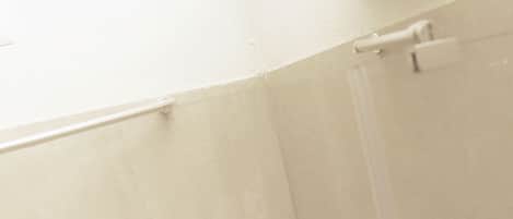 Une salle de bain équipée d’une douche, d’un système de ventilation et d’un miroir.