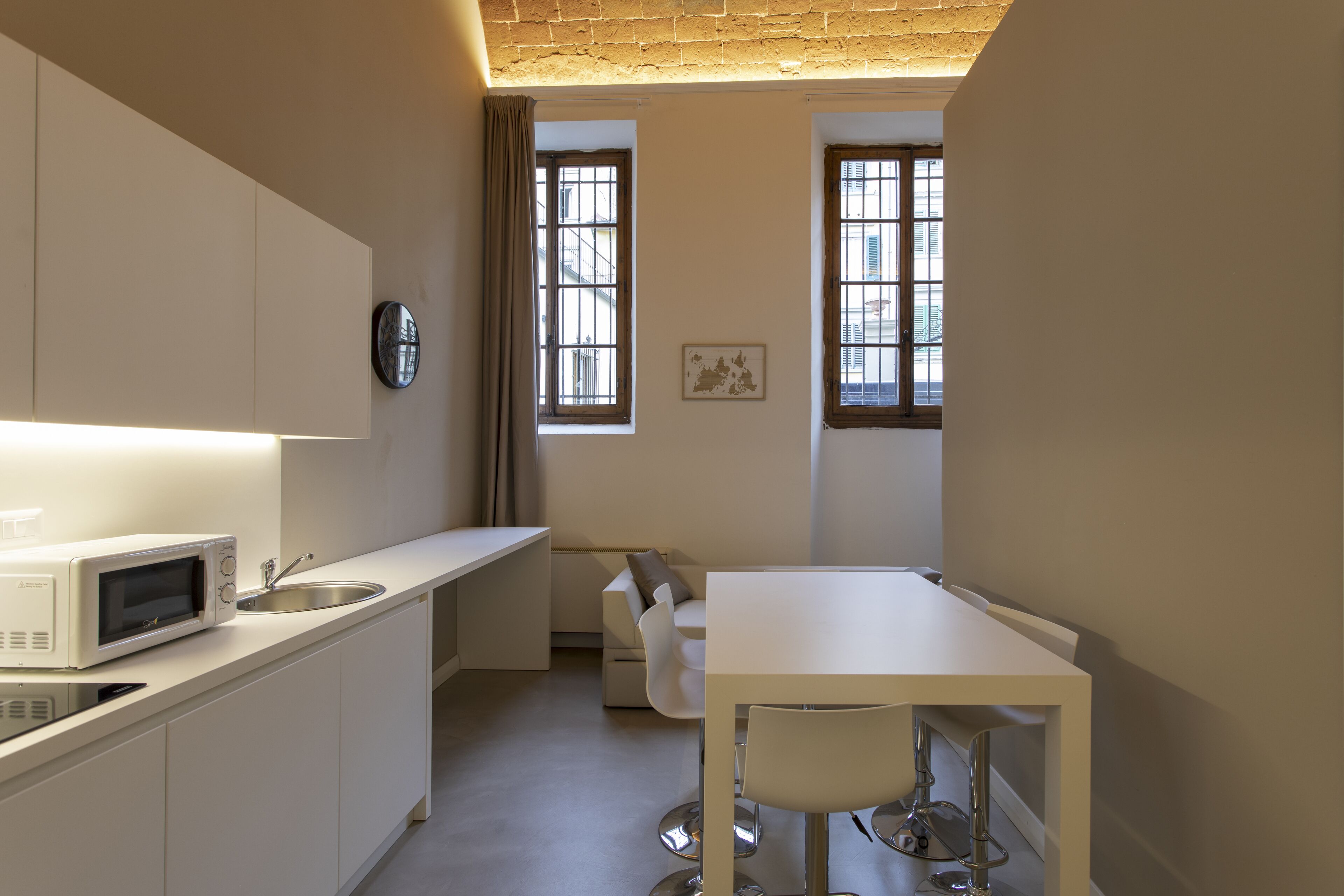A compact kitchen with a microwave, sink, and a dining area with a table and chairs.