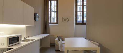 A compact kitchen with a microwave, sink, and a dining area with a table and chairs.