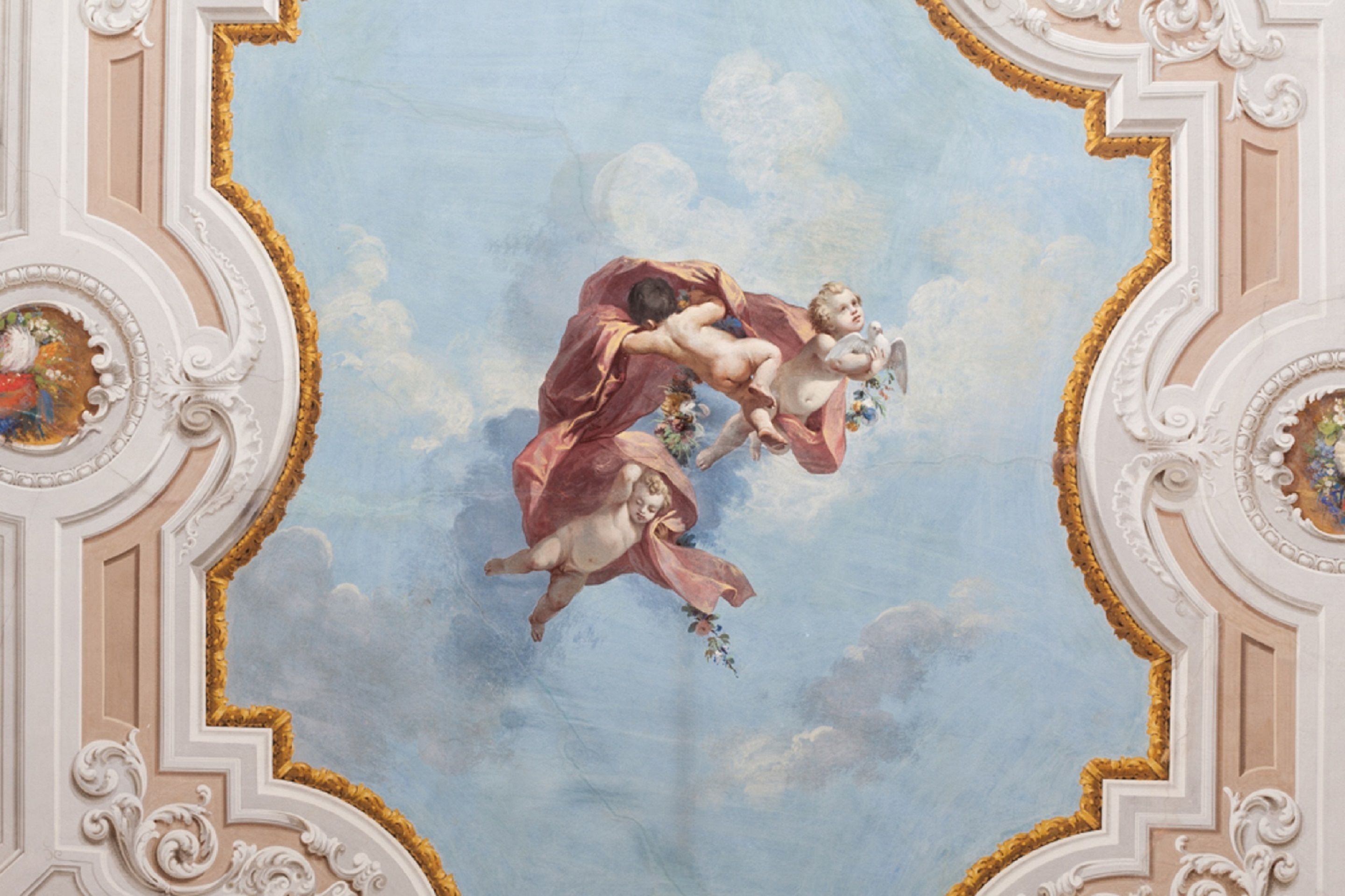 A ceiling with a classical fresco, ornate moldings, and a circular medallion.
