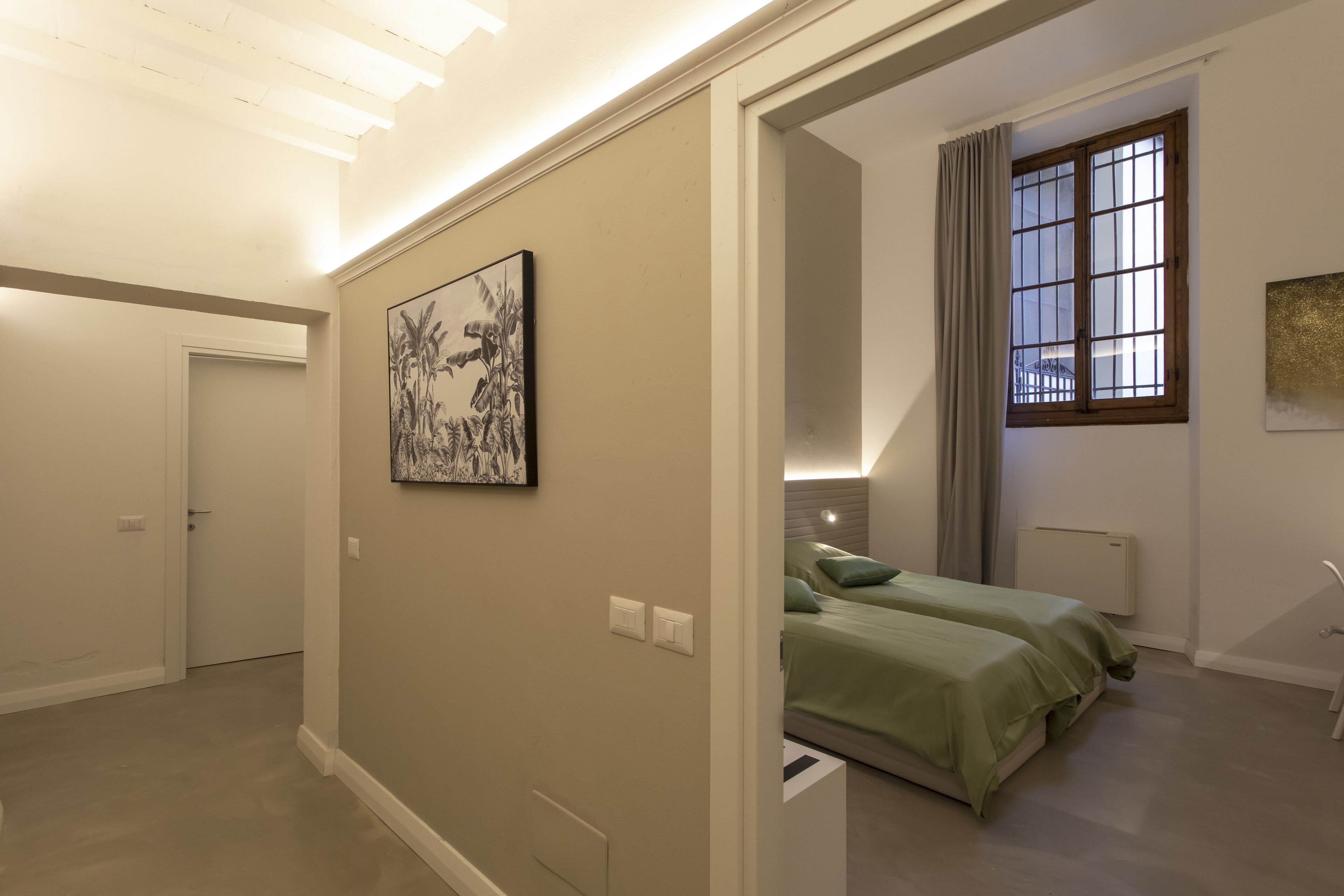 A bedroom with a bed, a nightstand, a window with curtains, and a door.