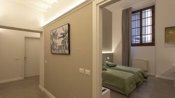 A bedroom with a bed, a nightstand, a window with curtains, and a door.
