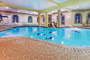 A swimming pool with clear water, a brick deck, and a waterfall feature.