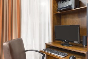 A wooden desk with a computer monitor, keyboard, and mouse.