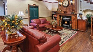 A traditional living room with leather sofas, a fireplace, and a clock on the wall.