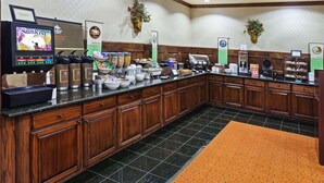 A hotel breakfast area with a self-service station, coffee makers, and various food containers.
