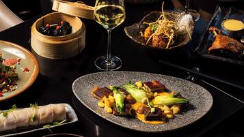 A dining table with various dishes, including a plate with meat, vegetables, and a glass of white wine.