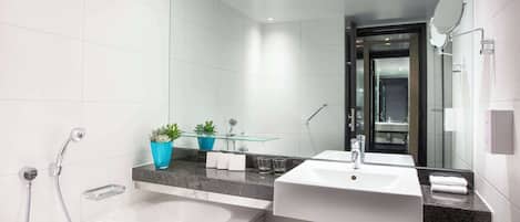 Une salle de bain moderne avec une baignoire, un lavabo et un miroir. Deux plantes en pot sont posées sur le comptoir.