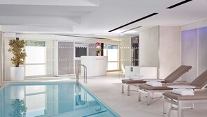 A modern hotel lobby with a reception desk, lounge chairs, and a pool area. - Park Plaza London Riverbank (London)