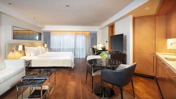 Ein Hotelzimmer mit Bett, Schreibtisch mit Fernseher, Stuhl, Sofa und Esstisch.