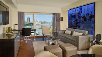 A modern living room with a view of the river and city landmarks, a glass coffee table, a sofa, and a decorative wall panel.