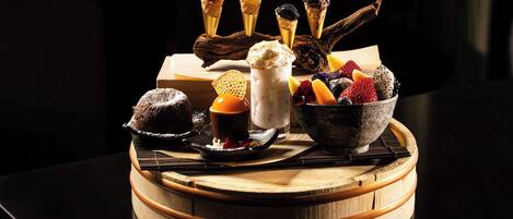 A dessert tray with ice cream cones, a chocolate dessert, and a bowl of mixed berries.