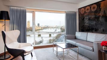 A modern living room with a view of a river and cityscape, including a bridge and iconic buildings.
