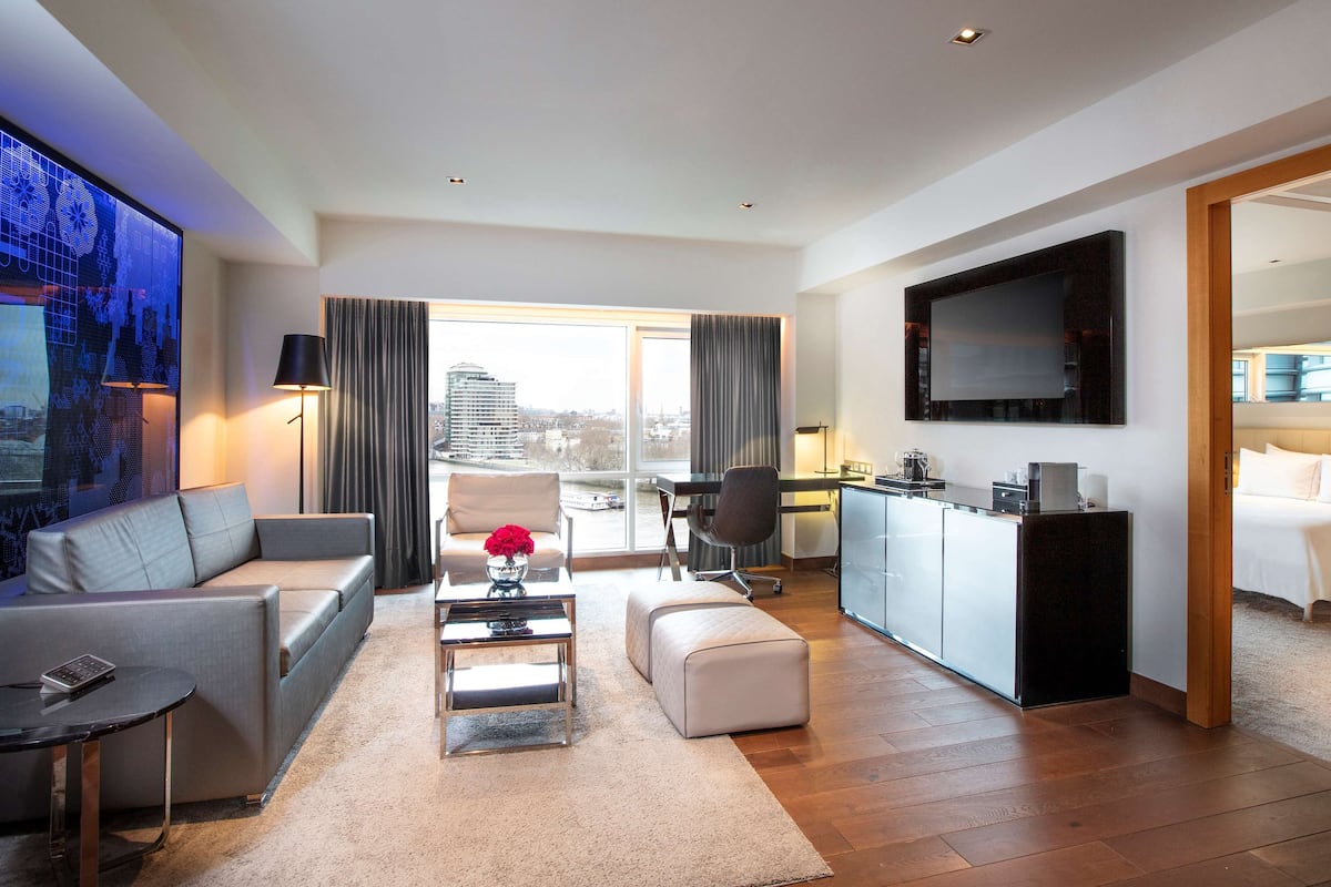 Una habitación de hotel moderna con sala de estar, comedor y dormitorio.