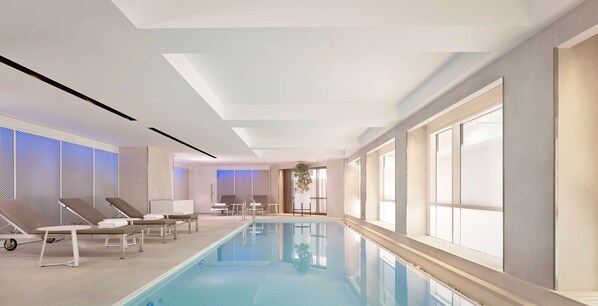 Una piscina interior moderna con sillones de descanso y una vista despejada.