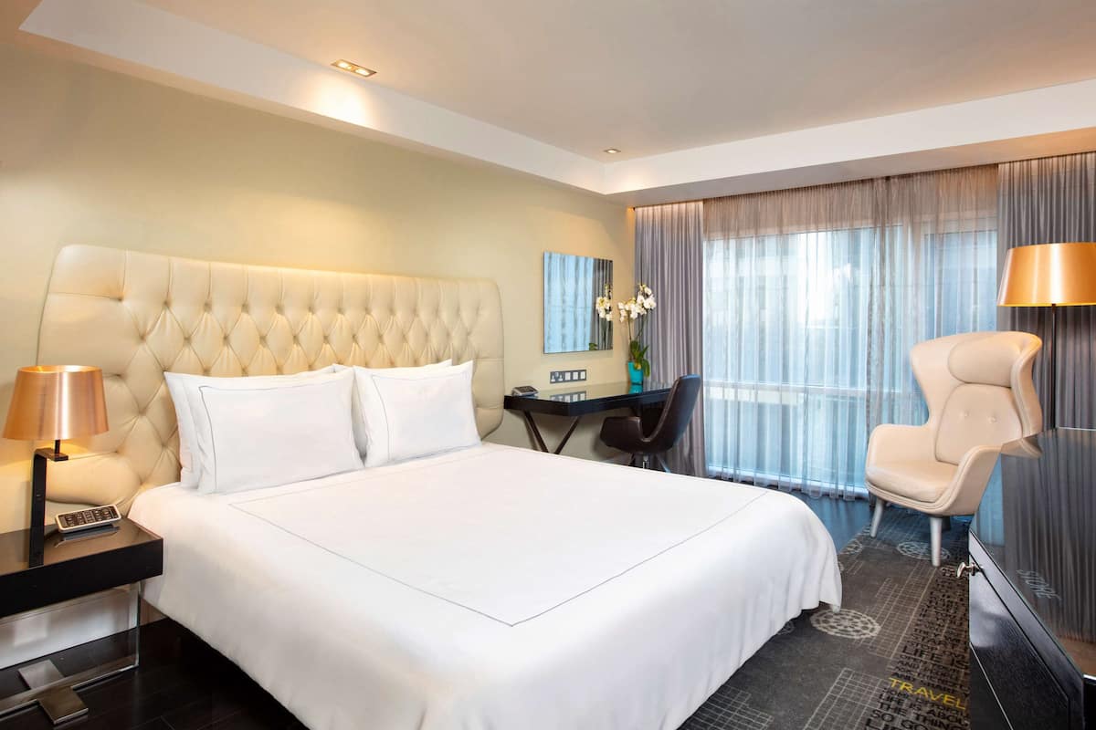 Una habitación de hotel con una cama grande, un escritorio, una silla y un televisor.