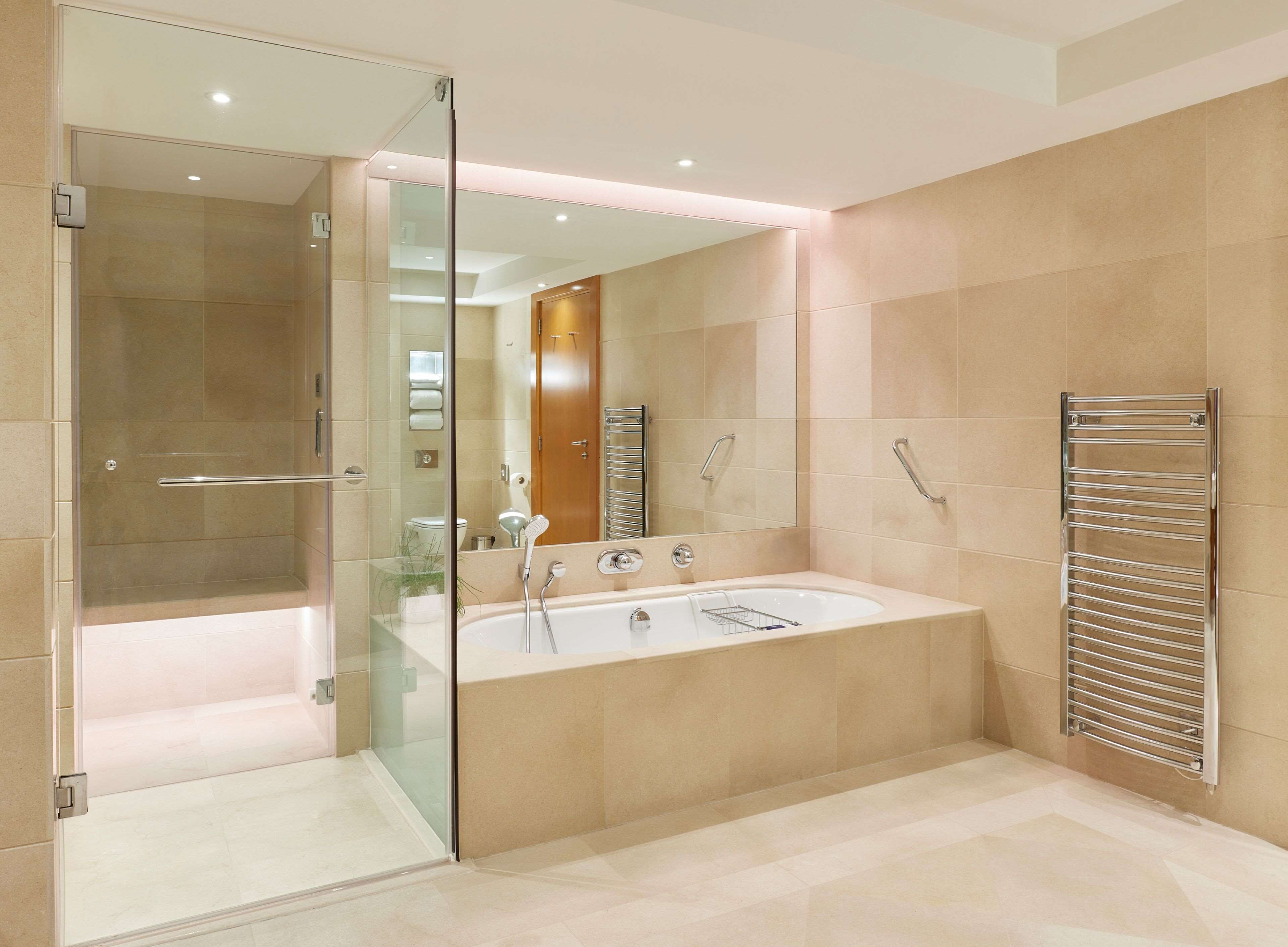 A modern bathroom with a glass shower enclosure, a freestanding bathtub, and a wall-mounted towel rack.