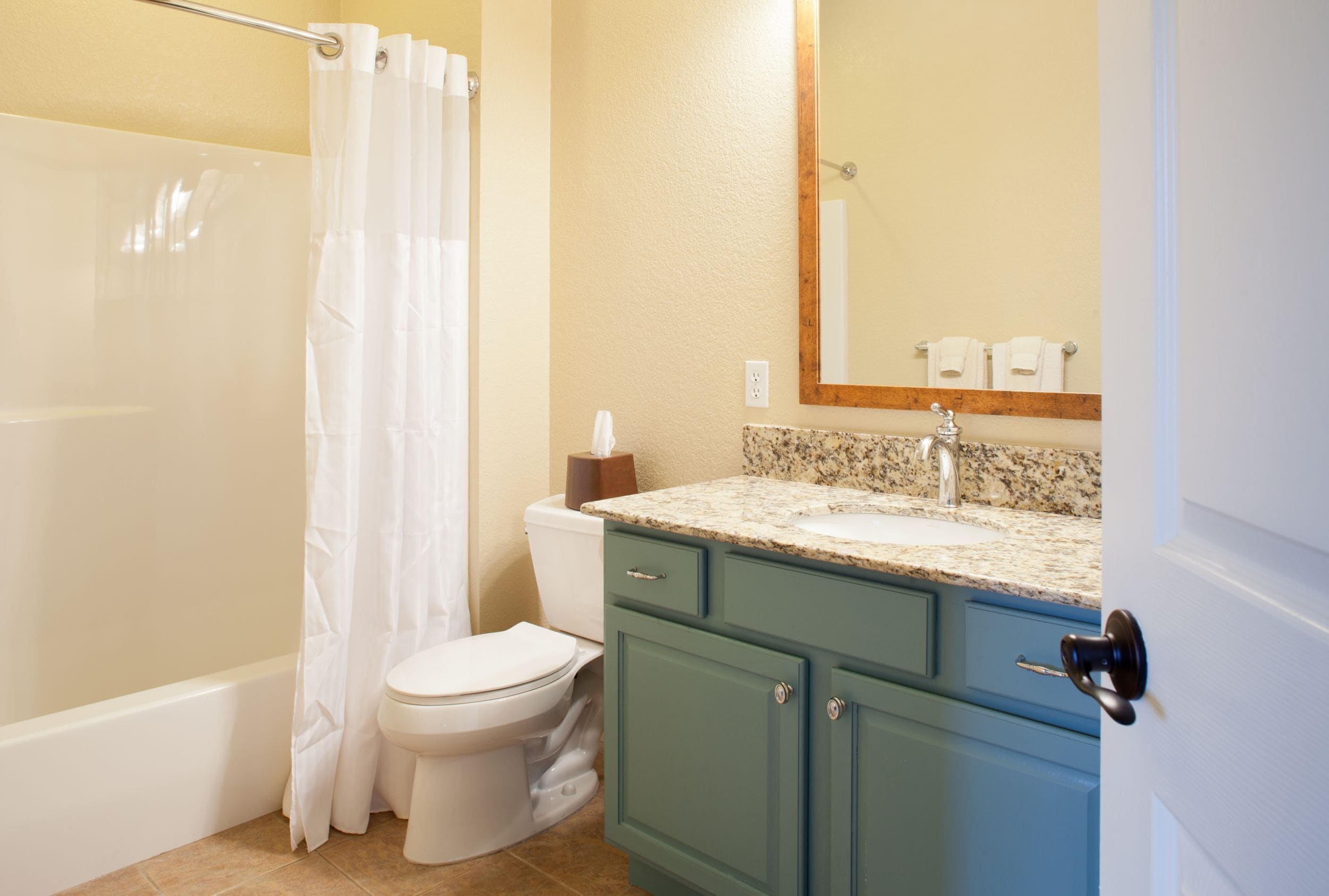 A bathroom with a shower, toilet, sink, and cabinet.