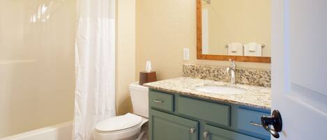 A bathroom with a shower, toilet, sink, and cabinet.
