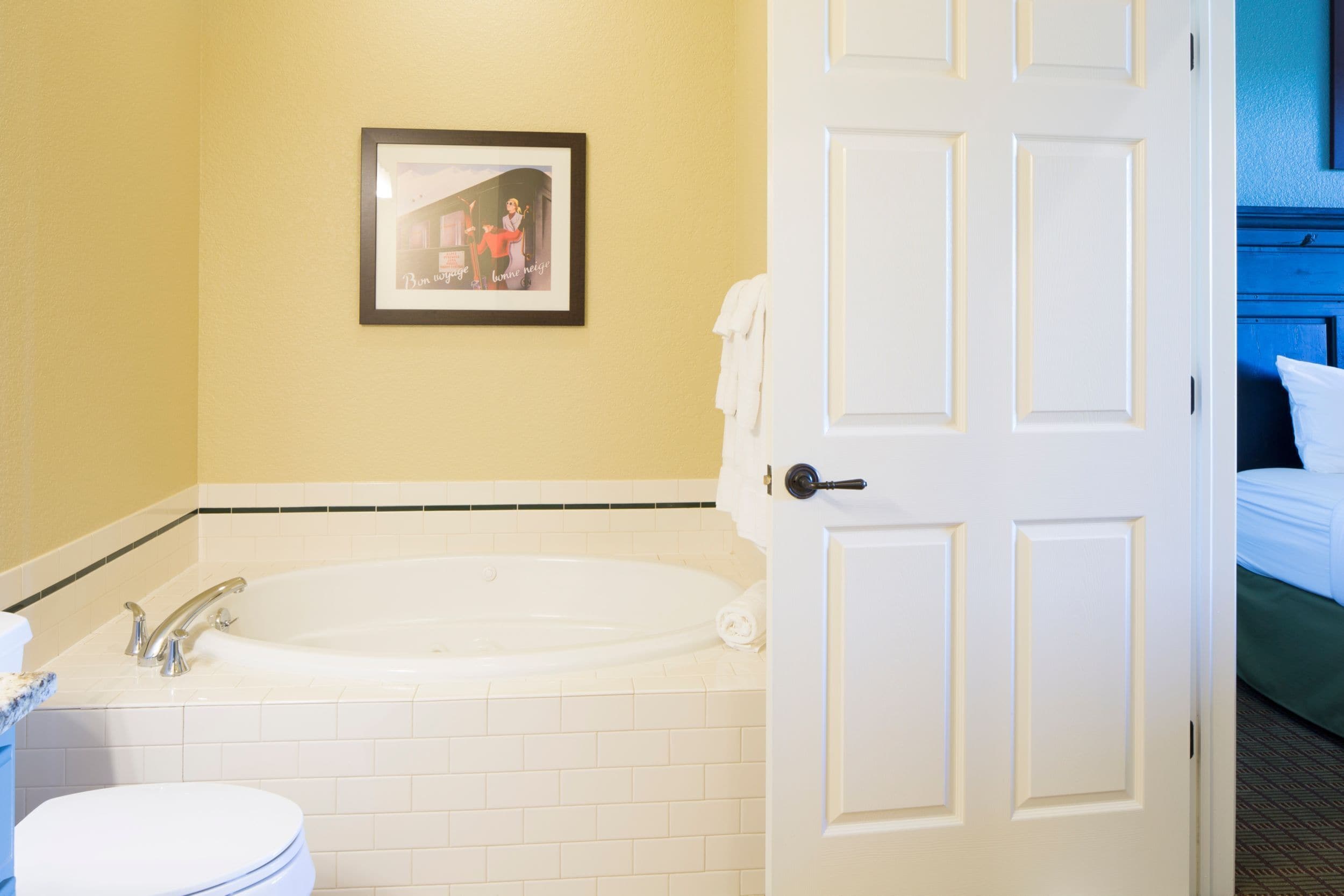 A bathroom with a bathtub, toilet, and a framed picture on the wall.
