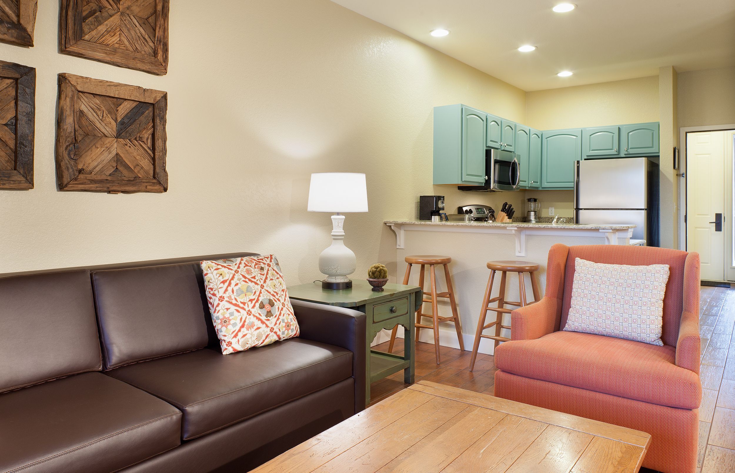 A modern living room with a brown leather sofa, a green side table, and a wooden coffee table.