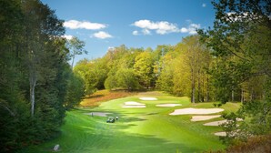 A golf course with a well-maintained green, sand bunkers, and a clear sky. - Mountain Run at Boyne (Boyne Falls)