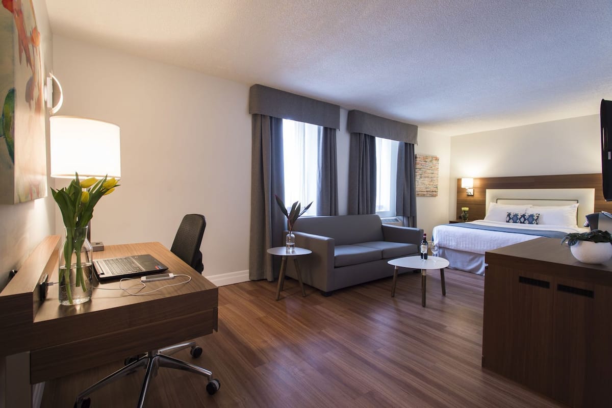 Una habitación de hotel con escritorio, silla, sofá, cama y televisor.