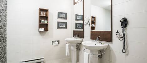 A bathroom with two sinks, a mirror, a hairdryer, and a heater.