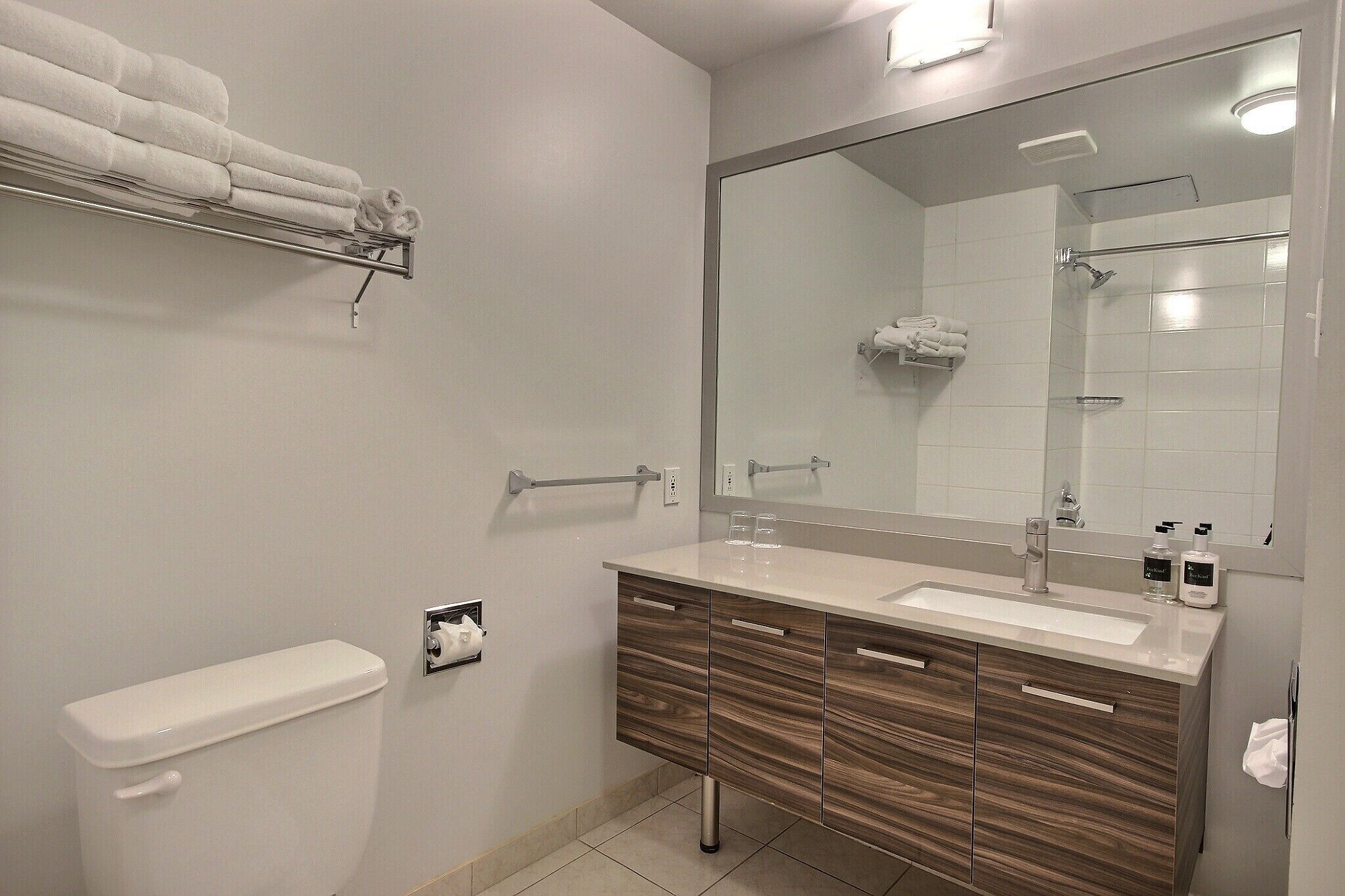 A modern bathroom with a large mirror, a sink, and a toilet.