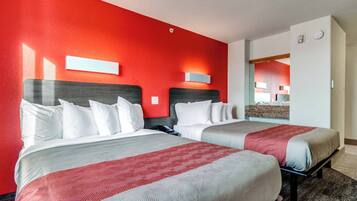 A hotel room with two beds, red walls, and a mirror.