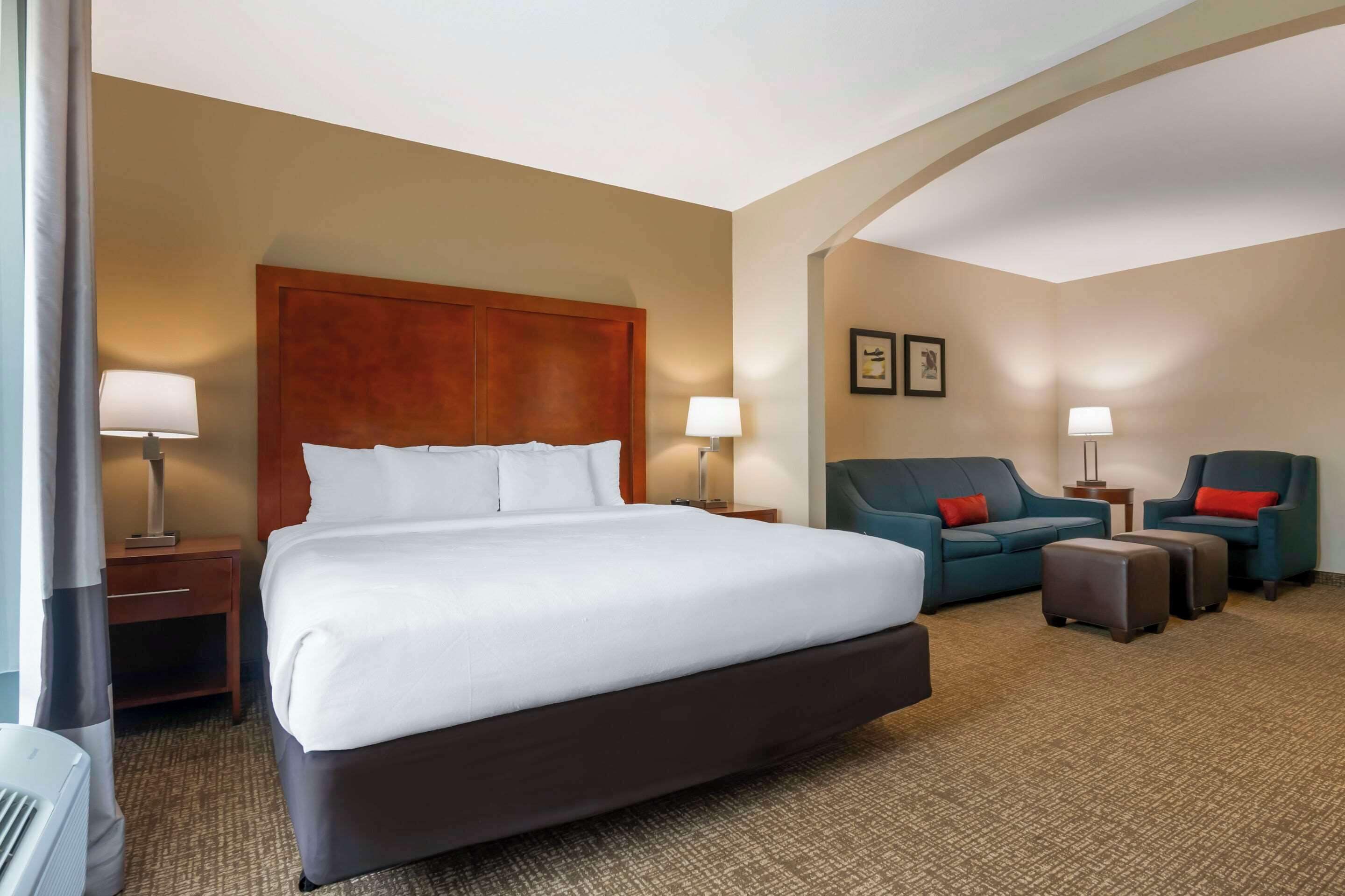 A hotel room with a large bed, two armchairs, a sofa, and a small table.