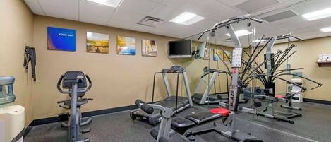 A gym with treadmills, elliptical machines, and weight stations.