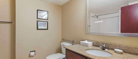 A bathroom with a toilet, sink, and mirror. There are two framed pictures on the wall.