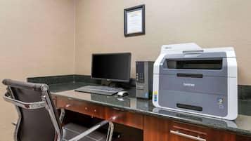 Ein Hotelbüro mit Schreibtisch, Computer, Drucker und Stuhl.