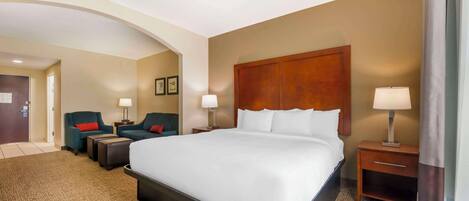 Una habitación de hotel con una cama grande, dos mesitas de noche con lámparas, un sofá y una silla.