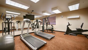 Un gimnasio con cintas de correr, elípticas y una bicicleta estática.