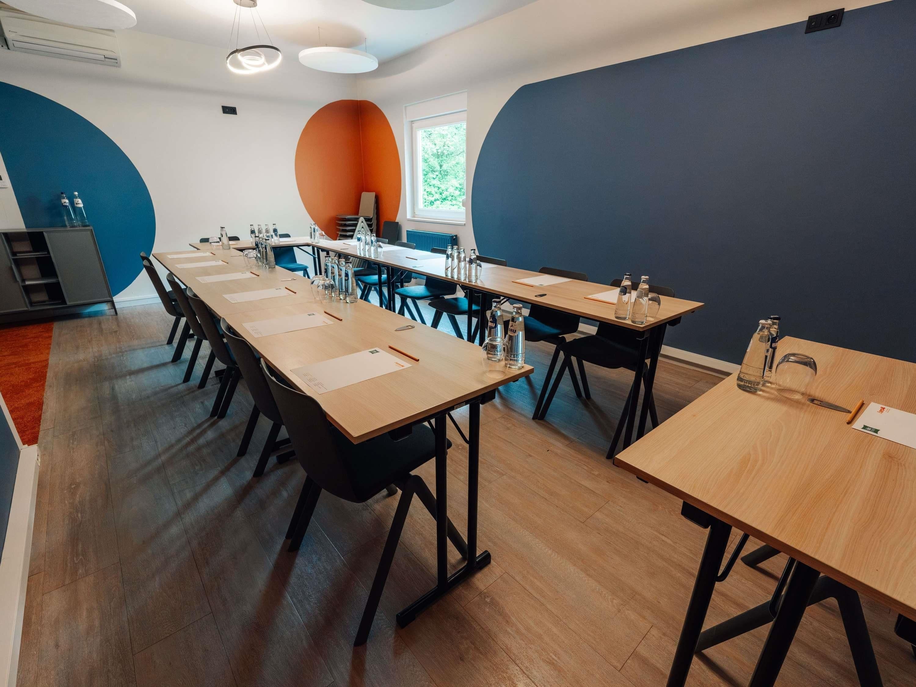 A conference room with long tables, chairs, and water bottles.