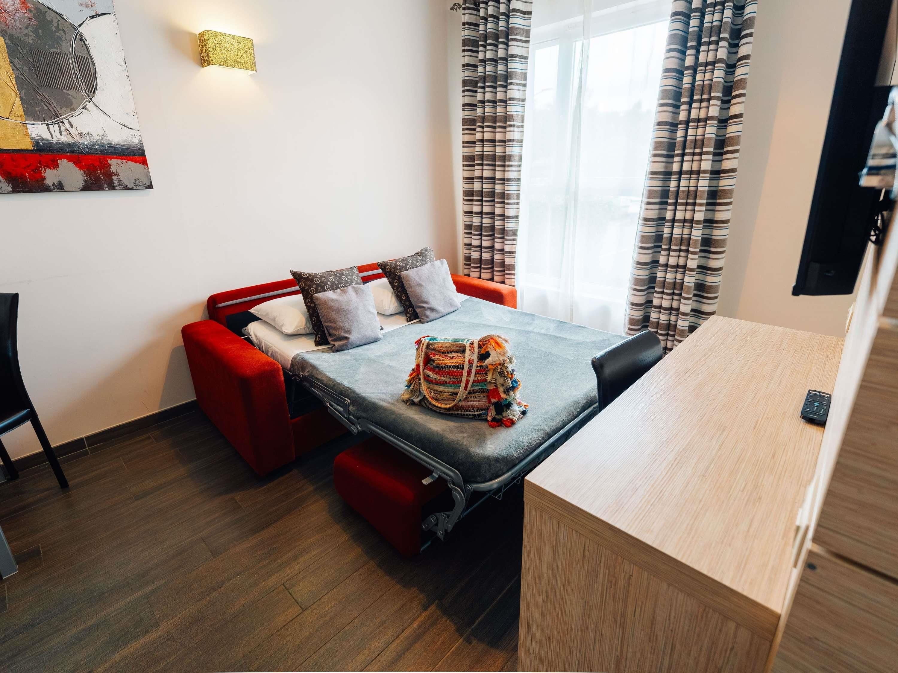 A compact room with a bed, a small table, and a sofa.